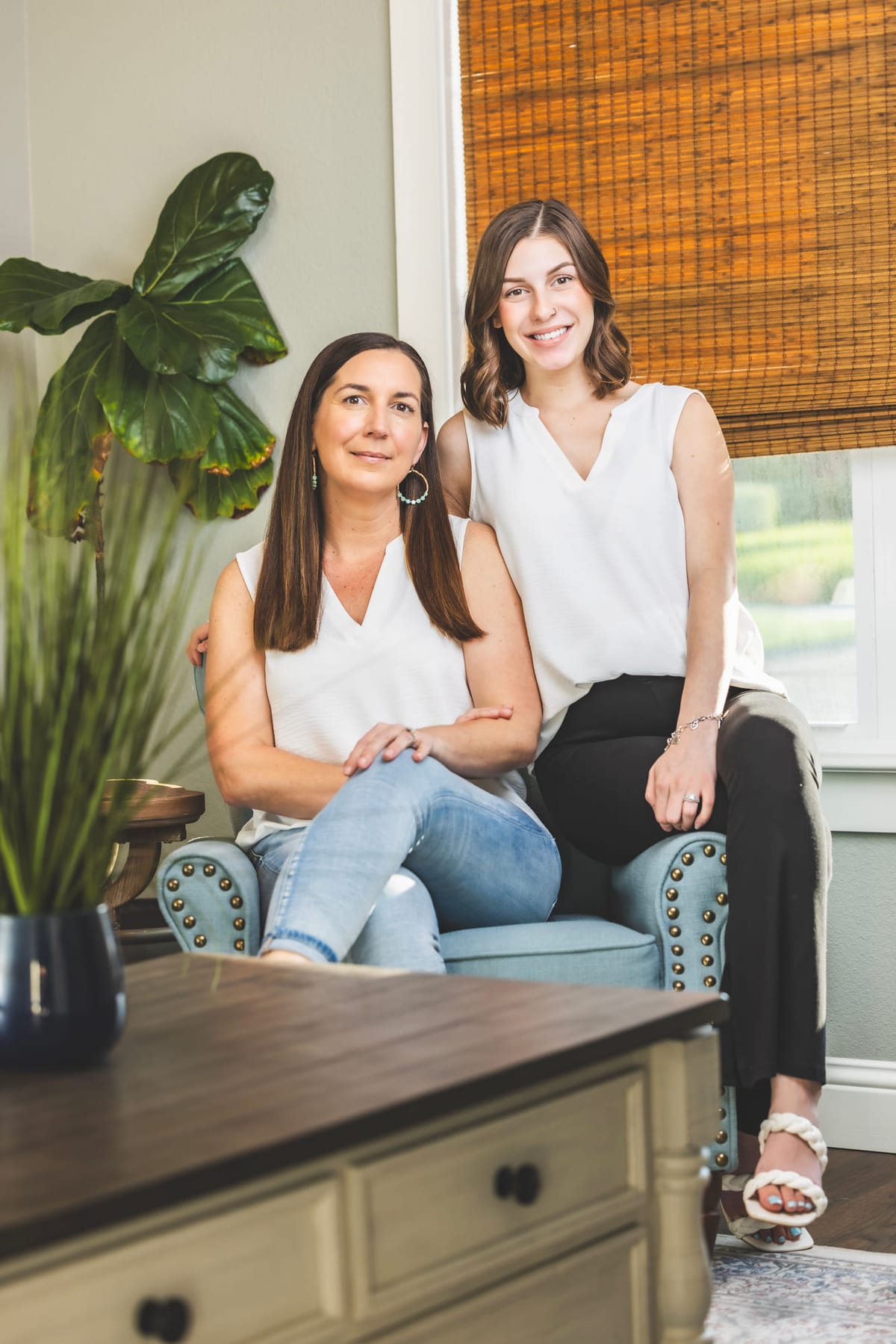 Two colleagues photographed together in an office, one seated on the desk.