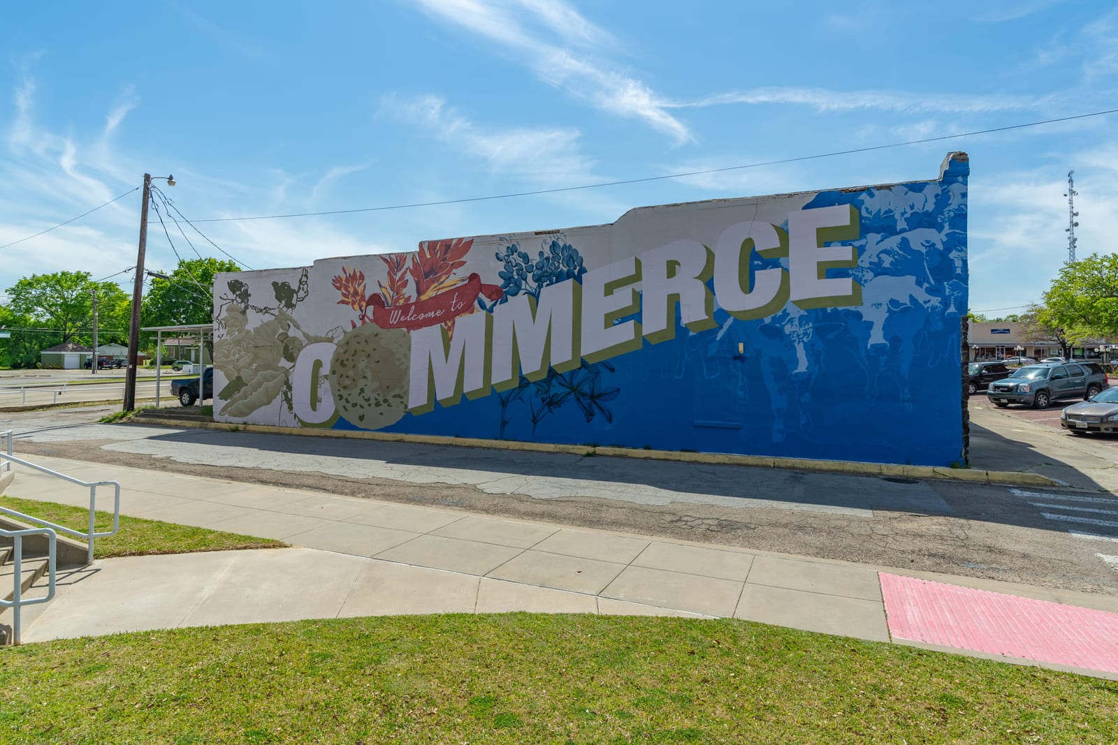 A painted COMMERCE mural running the length of a downtown wall beside the sidewalk.