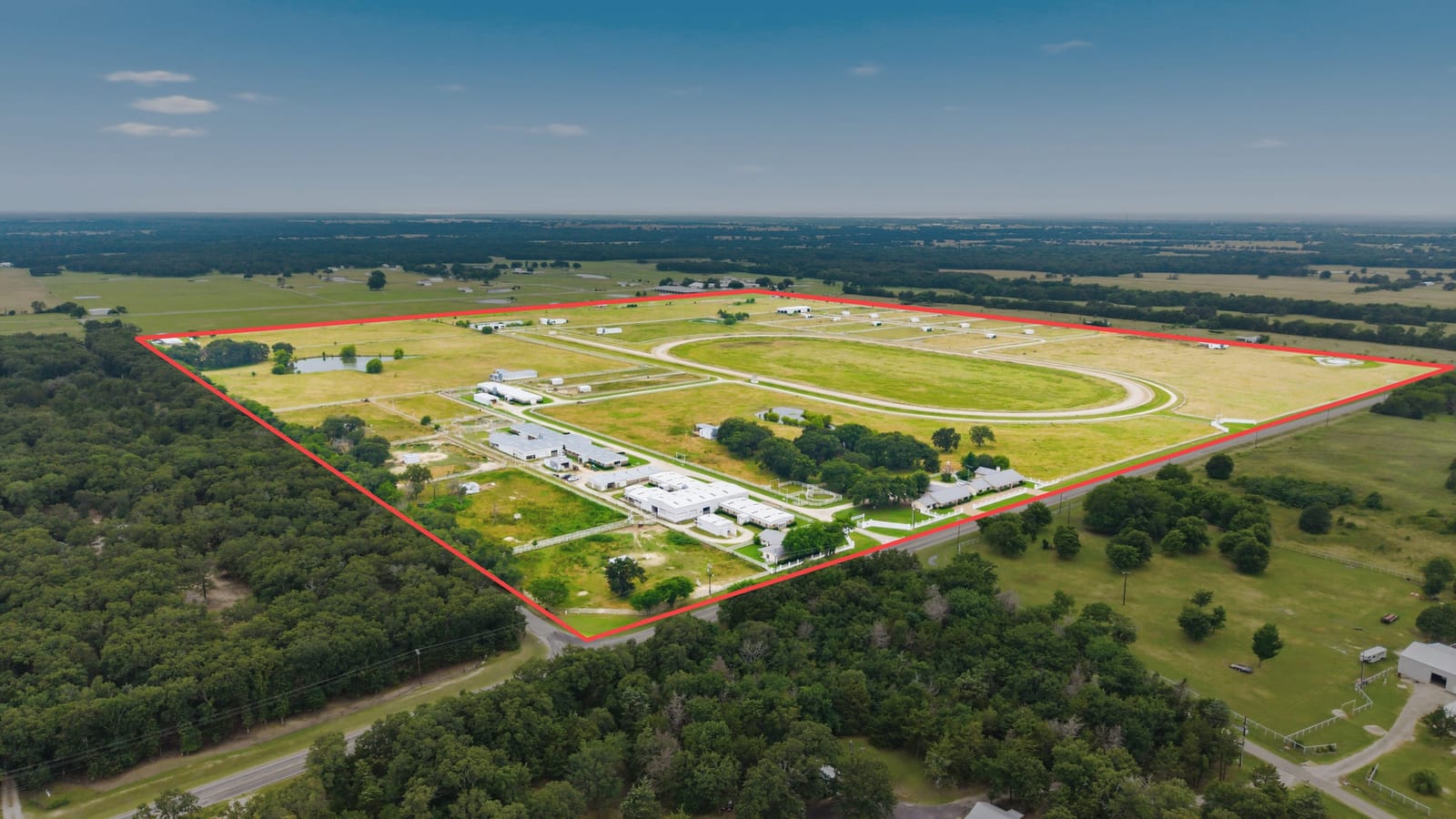 An aerial of a racetrack and its infield, the property boundary drawn onto the frame.