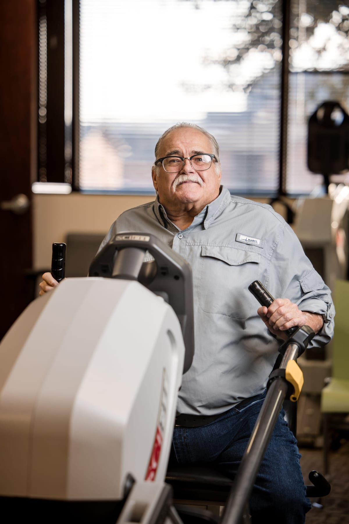 A patient working on a rehabilitation machine beside a window.