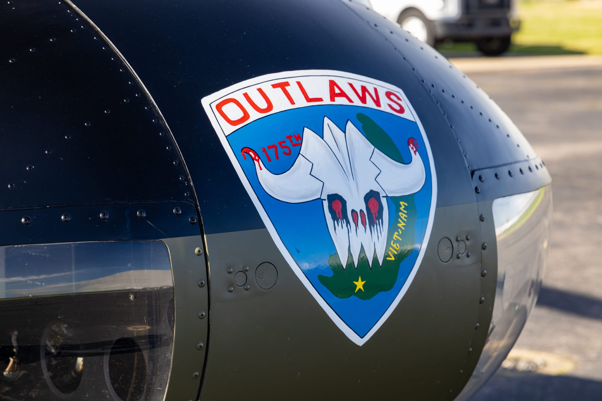 The nose of a helicopter photographed close, its squadron badge painted on the panel.