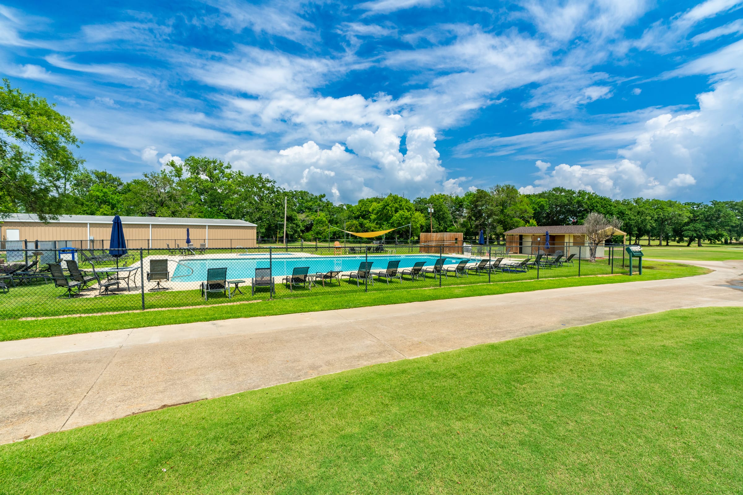 The grounds of a resort clubhouse, pool and cabanas beyond a wide sweep of mown grass.