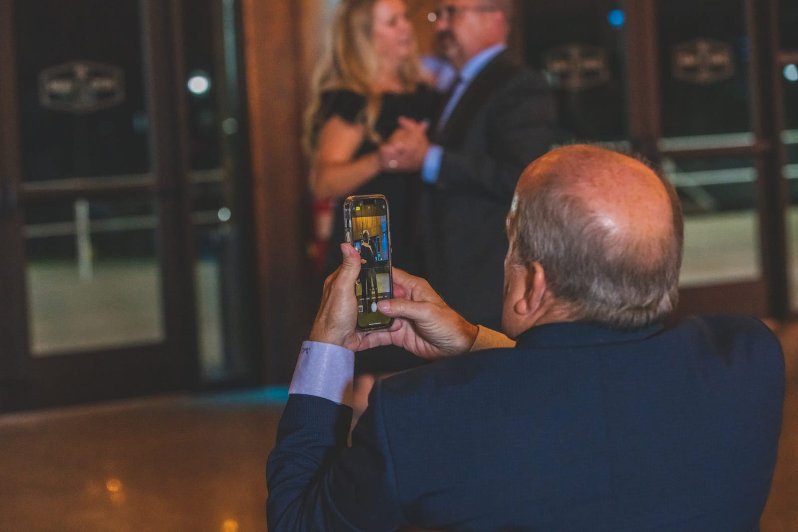 Two guests raising glasses to each other across a gala floor.