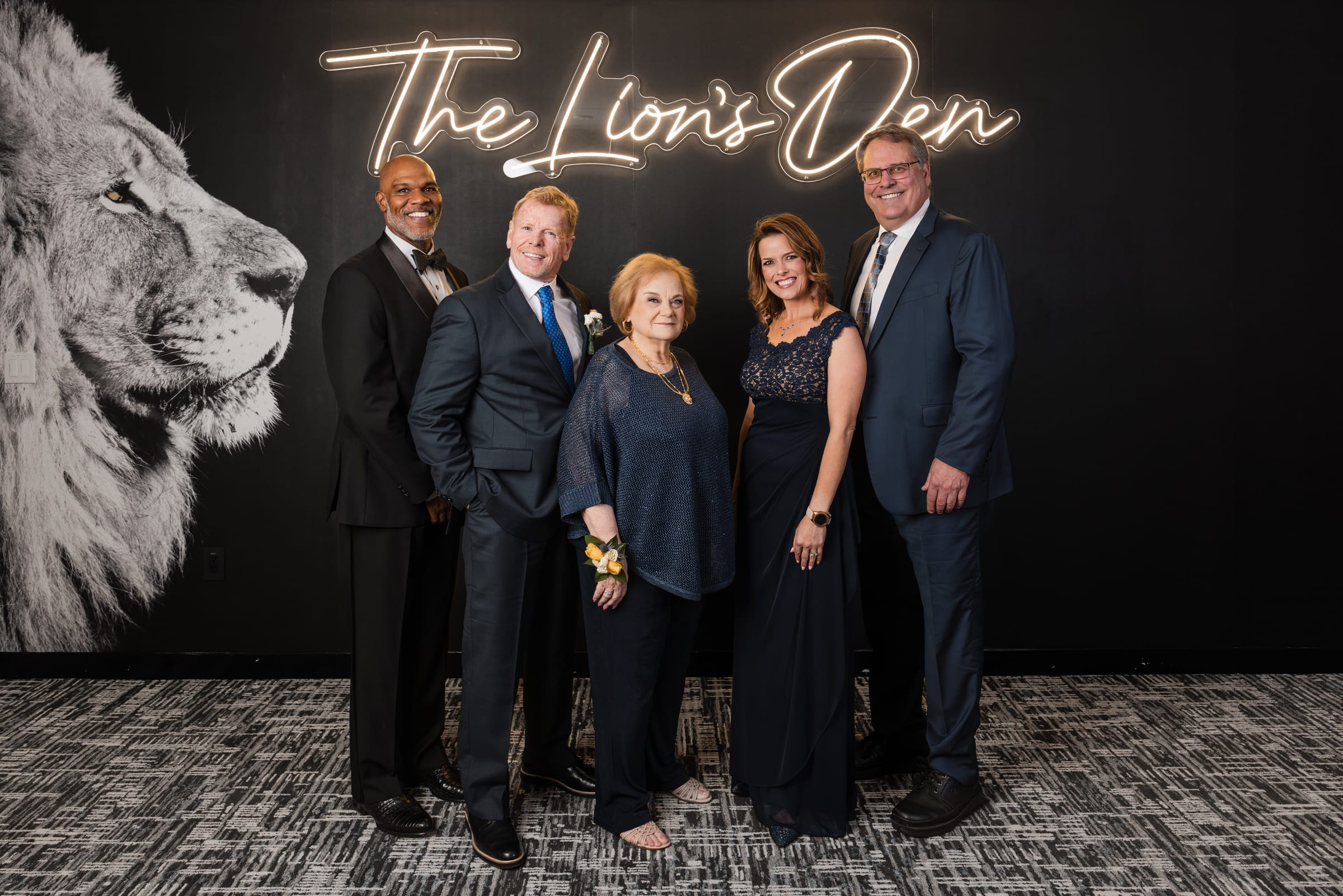 Five honourees in evening dress photographed together beneath a lit backdrop at an awards gala.
