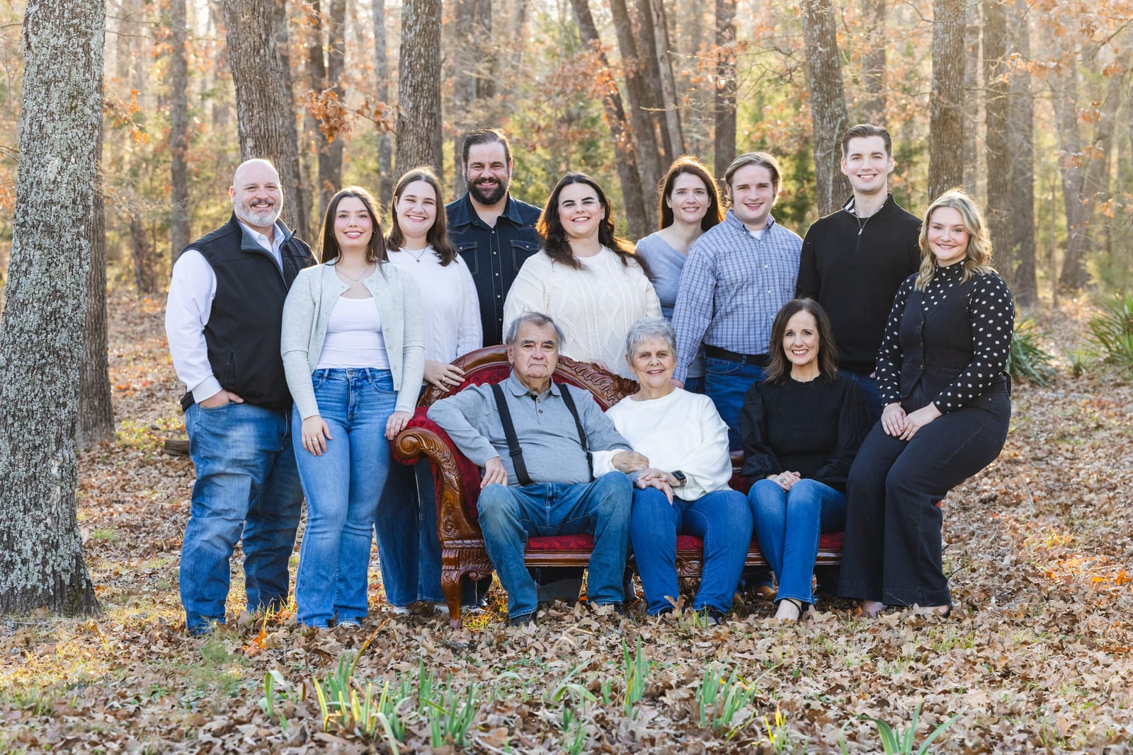 An extended family lined up in autumn woods, the eldest seated at the centre.
