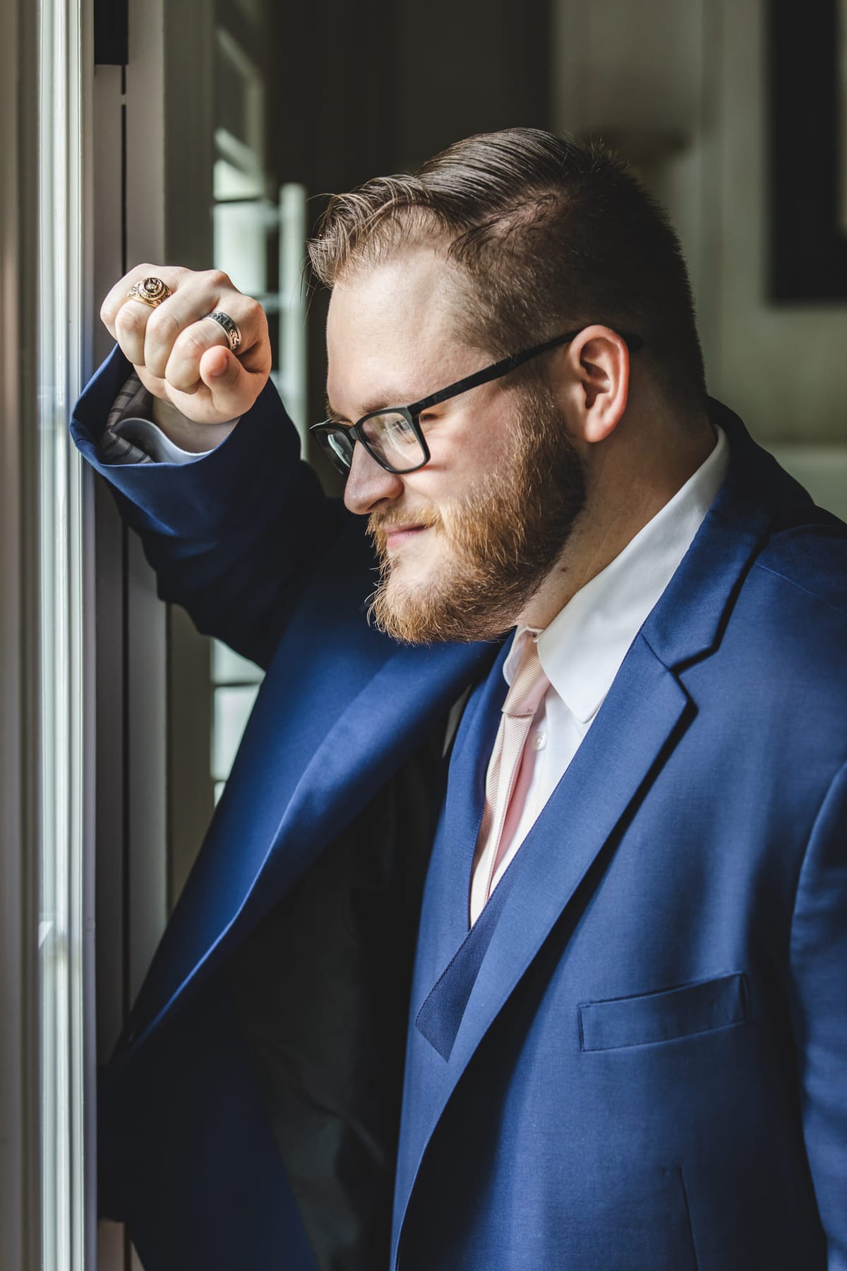 A portrait in a blue suit leaning in a doorway, one fist raised.