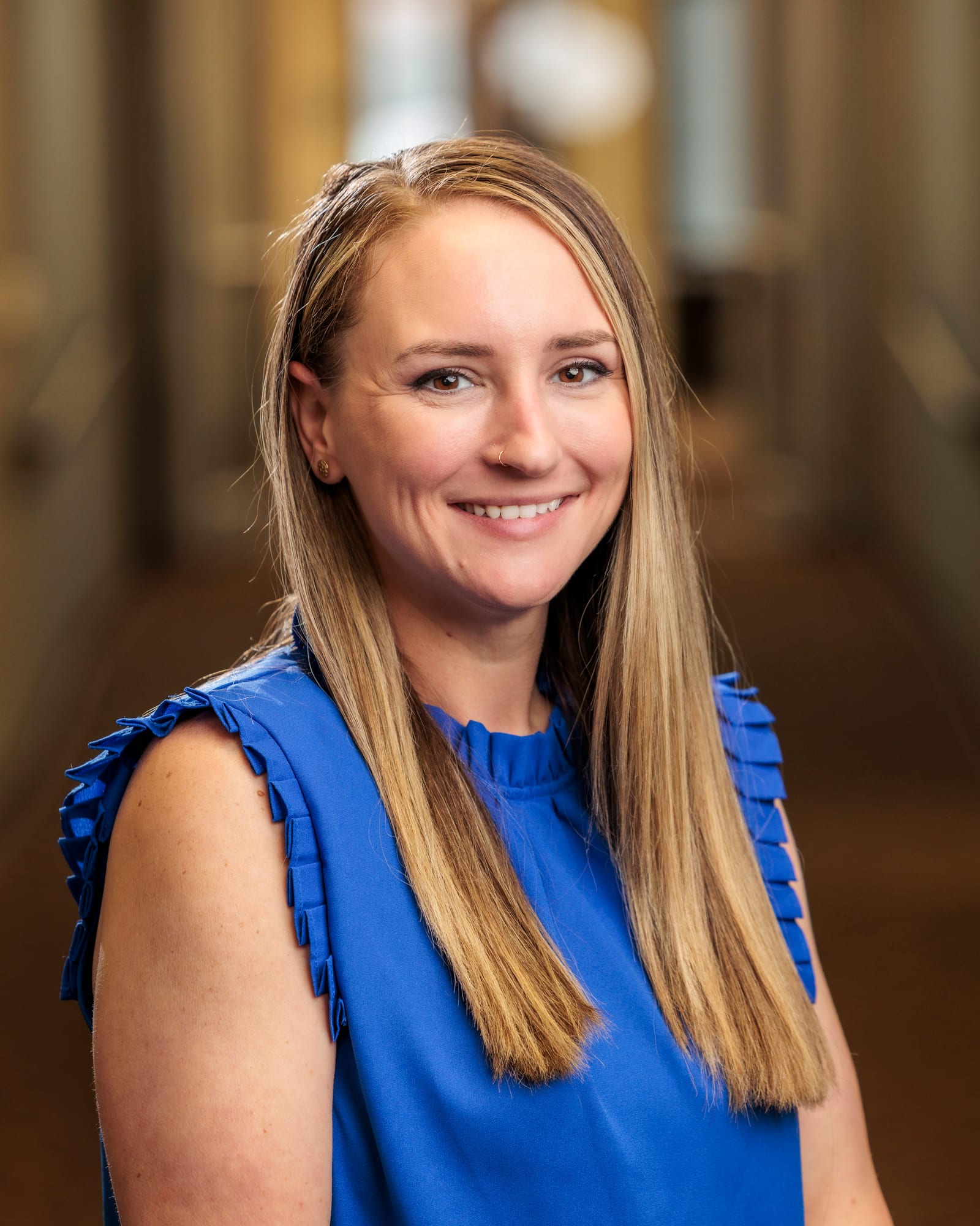 A close corporate headshot in a bright blue sleeveless top.