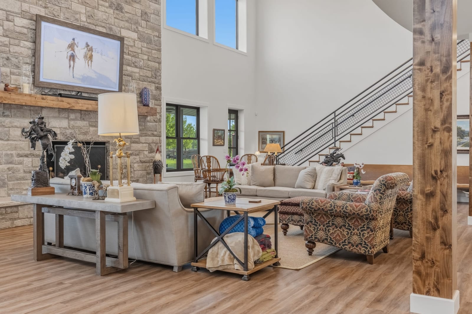 A great room with a stone fireplace, open stair and a mezzanine looking down over the seating.