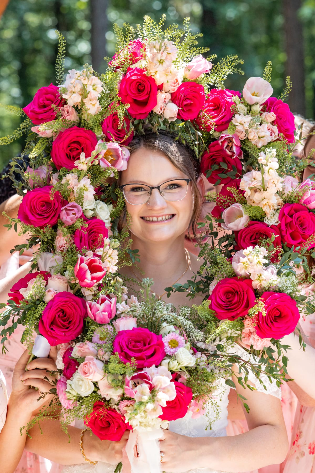 A senior’s face framed by a dense wall of pink and red garden roses.