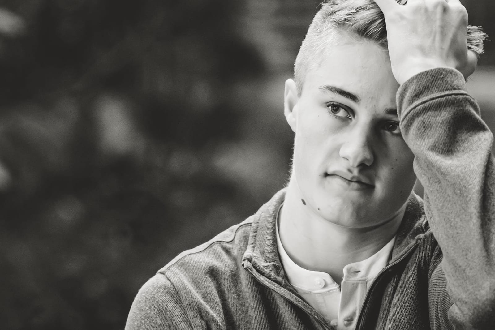 A black-and-white senior portrait, one hand pushed back through his hair.