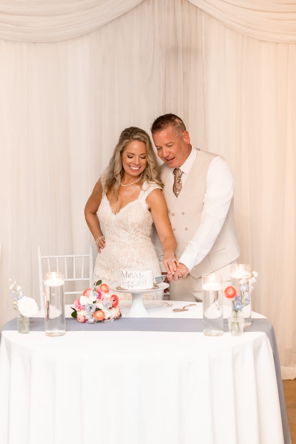A couple cutting the cake together at the reception table.