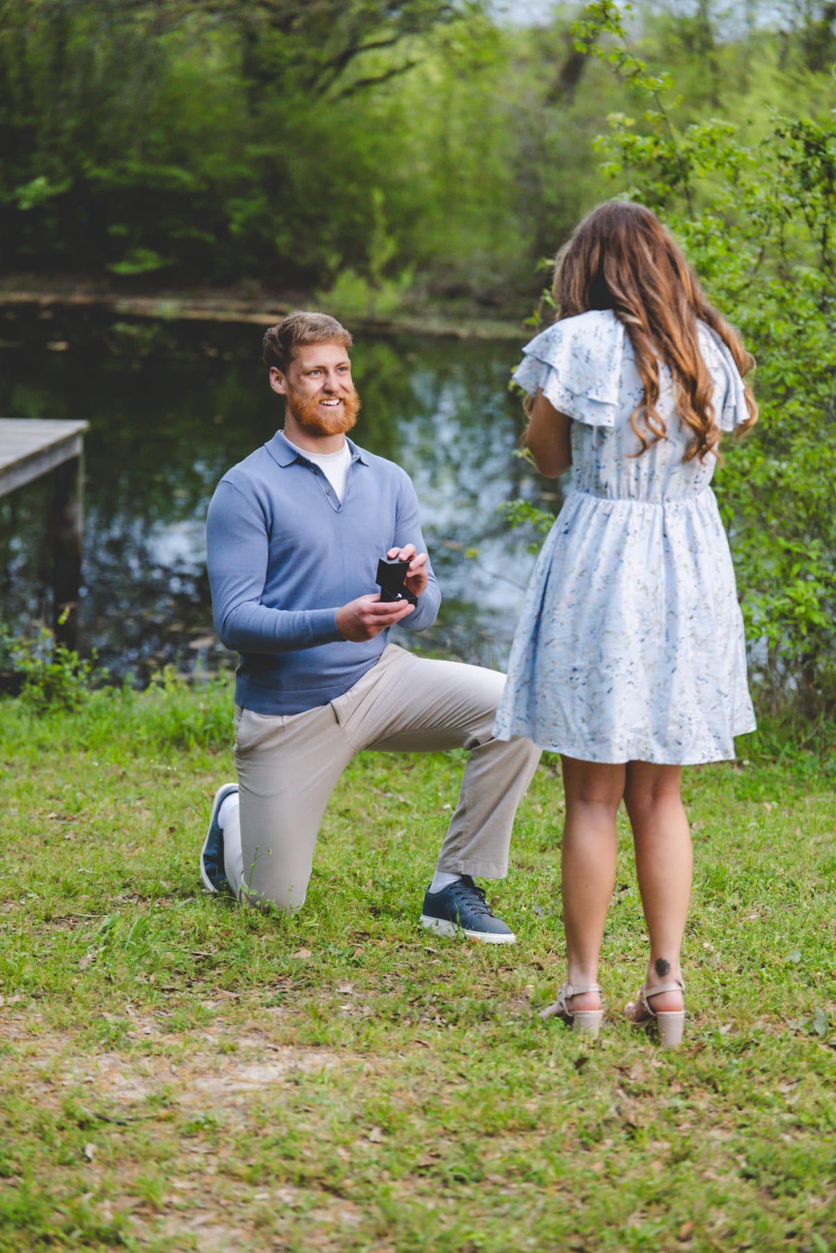 A proposal on one knee at the edge of a pond, the ring box open.