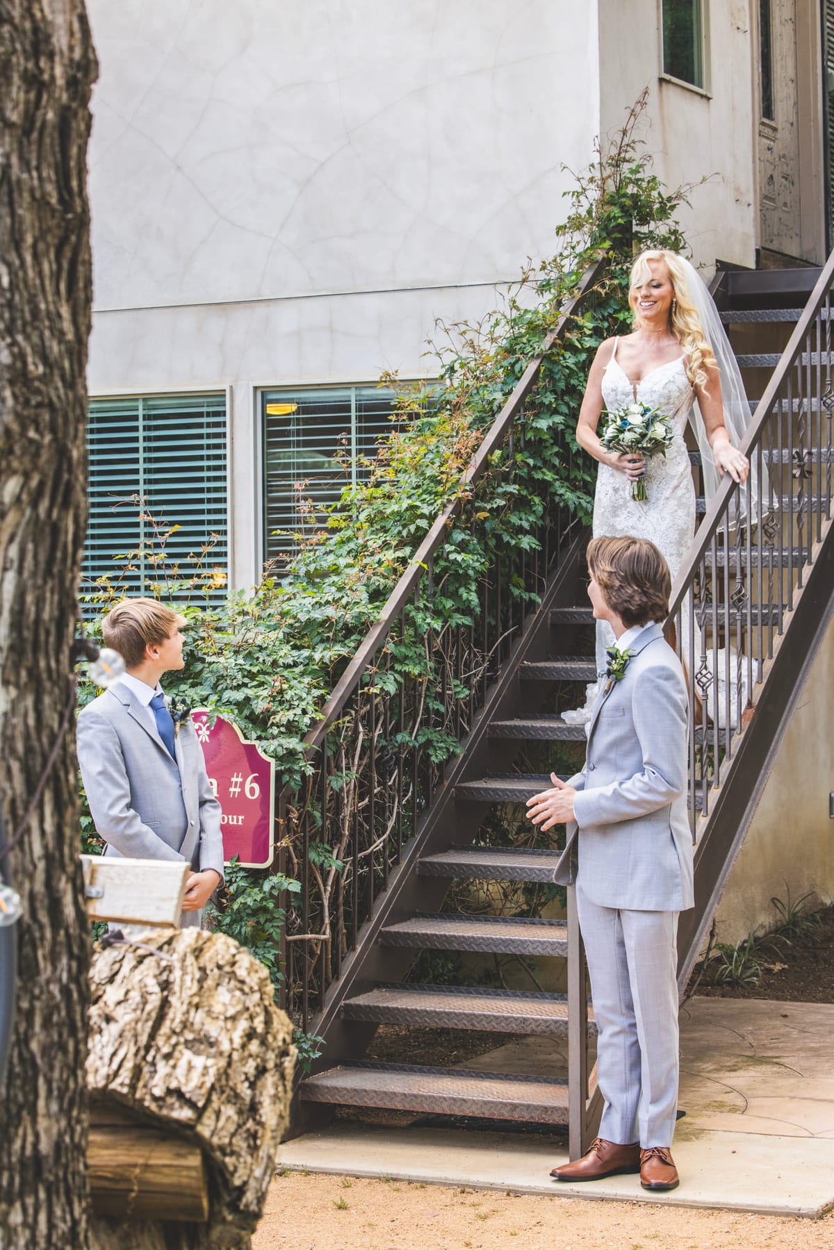 A bride coming down an outdoor staircase toward the groom waiting at the bottom.